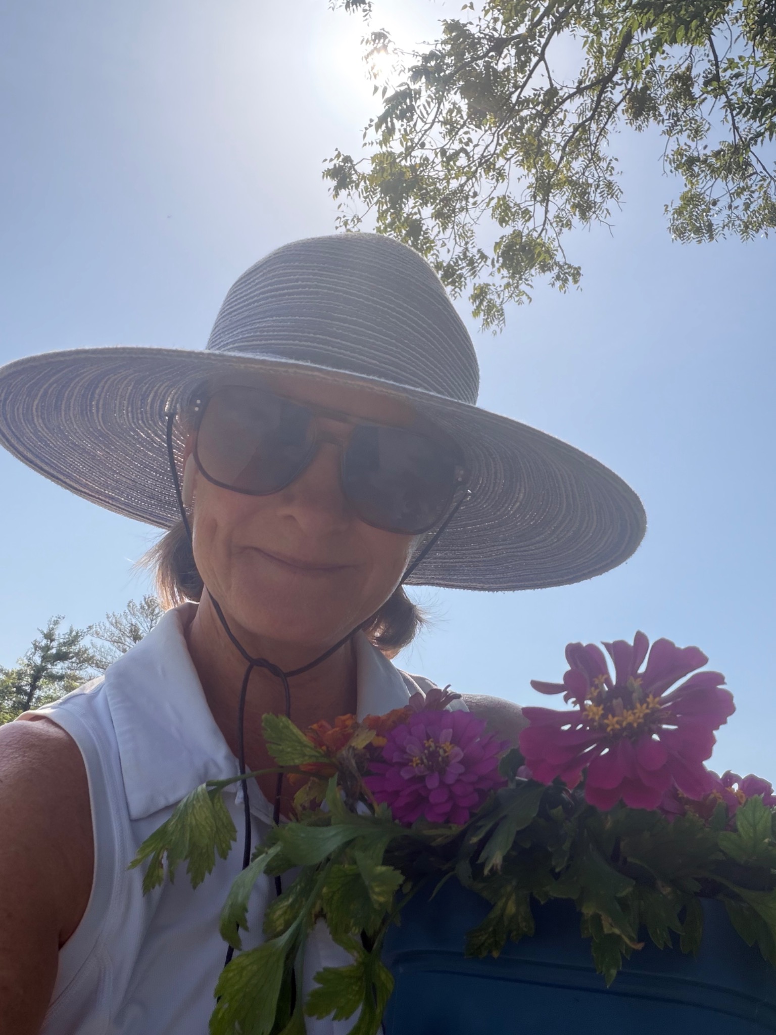 Allison Greiner holding flowers beneath a wide-brimmed hat
